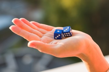 Dice 1 3 in the female hand, sunset background. Gambling devices.