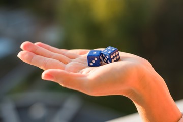 Dice 1 4 in the female hand, sunset background. Gambling devices.