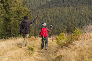 Fototapeta premium Young couple walking on the mountains road in autumn time 