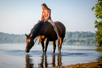 Reiterin mit Pferd im See