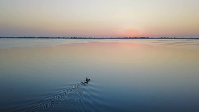 aerial footage of man kayaking on lake during sunset