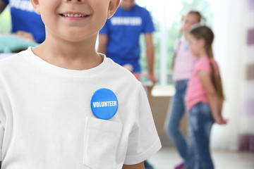 Little boy in shirt with volunteer button on blurred background