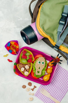 Open Halloween lunch box with school lunch on grey concrete background