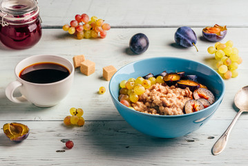 Porridge with plum, grapes and cup of coffee