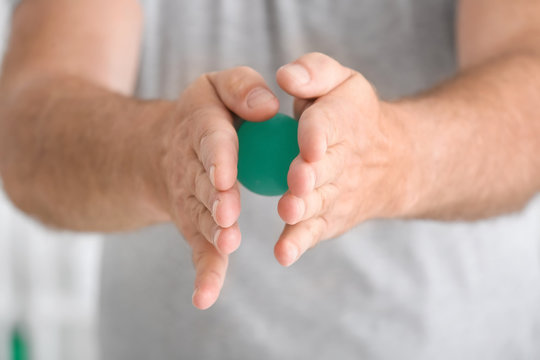 Senior man doing exercises with rubber ball on blurred background