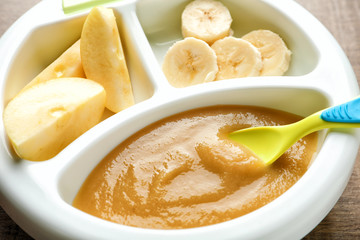 Section plate with baby food and fresh fruits, closeup