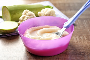 Plastic bowl with baby food on table