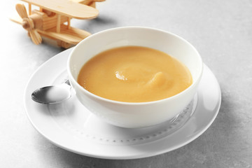 Ceramic bowl with baby food on grey background