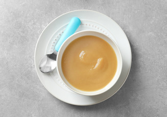 Ceramic bowl with baby food on grey background