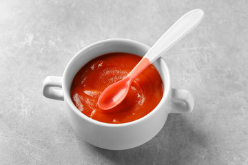 Ceramic bowl with baby food on grey background