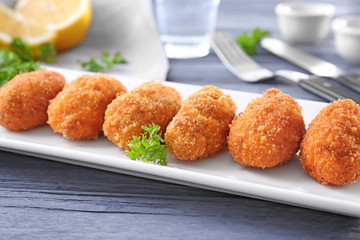 Plate with delicious salmon croquettes on table, closeup