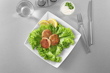 Plate with delicious salmon patties on table