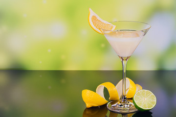 Glasses of cream liqueur with lime and lemon on green background with reflection.