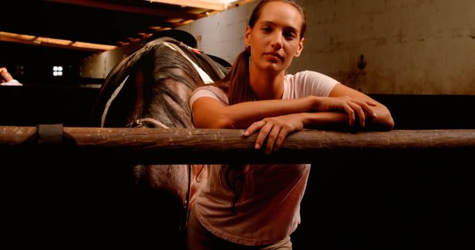 Woman standing with the horse in the stable 