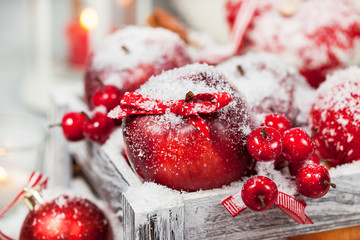 Christmas composition with red apples, balls, cinnamon, snow and candles