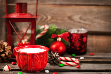 Christmas time red cup of milk and latern with candle light, holiday decorations around