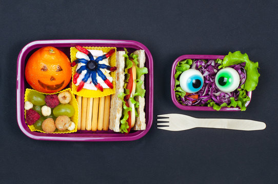 Open Halloween lunch box with school lunch on black background