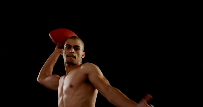American football player throwing ball against black background 