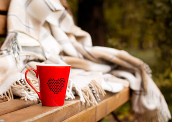 red mug wrapped in a blanket on a bench