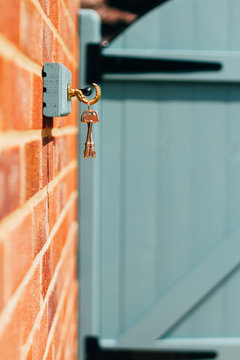 Keys hang on a wall by a blue garden gate