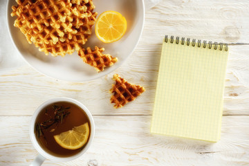Tea with lemon, wafer and notepad. Copyspace
