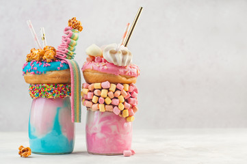 Twee freak shakes topping met donut en meringues over grijze achtergrond met kopieerruimte