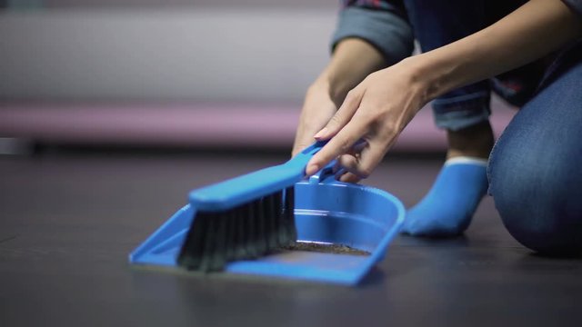 Migrant female worker dusting the floor with a brush, underpaid employment