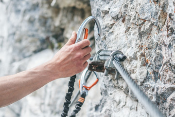 close up of a male climber hooking his carabiner in a safety steel rope