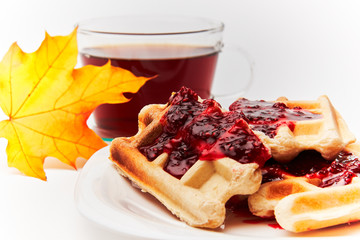 A cup of tea and crispy wafers./A cup of tea and crispy wafers poured with raspberry jam. White dishes. White background.