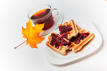 A cup of tea and crispy wafers./A cup of tea and crispy wafers poured with raspberry jam. White...