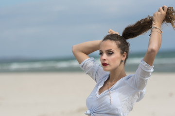 Fototapeta na wymiar Young cute woman wear tied shirt on the beach fixing her ponytail