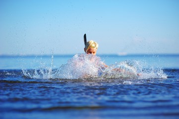 Summertime. Young blond woman bathed in the sea. Girl having fun splashing the water, raising a...
