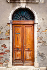 Fototapeta na wymiar Vintage wooden door on an old wall with exposed bricks