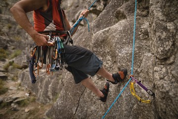 Man with various safety equipment climbing mountain