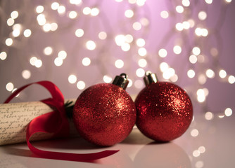 Two red Christmas balls on a reflective surface on a bokeh background. Winter holidays concept.