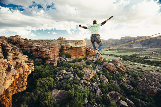 man balancing on a highline or tightrope high over a valley