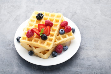 Sweet waffle with berries on grey wooden table