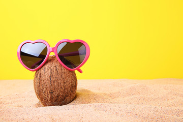 Coconut with sunglasses on the beach sand