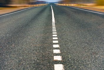 The picturesque landscape and the Sunrise over the road. Asphalt road with marking. With the blur.