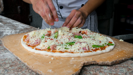 Cheese being spread on tomato sauce on pizza base. Selective focus