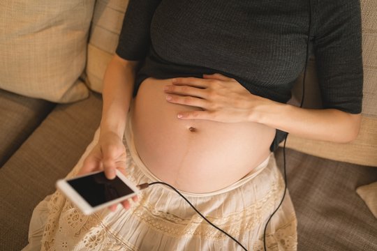 Pregnant woman using mobile phone while touching her belly
