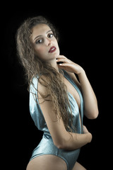 Fototapeta premium Wet look from a cute woman, studio in black background, wet skin and hair, wear blue shine one piece swimsuit