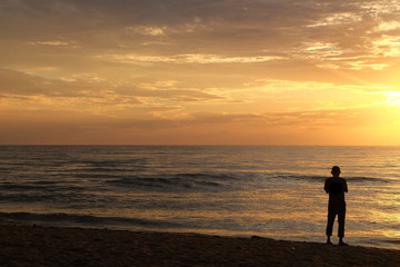 Fototapeta na wymiar Silhouette of man at the sea at Cha-am Beach, thailand at the sunrise
