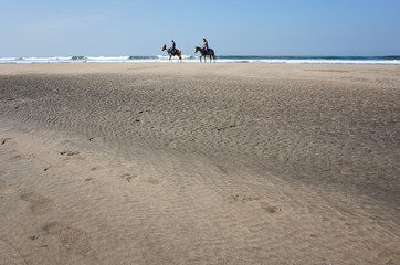 two riders ride on the beach at sea