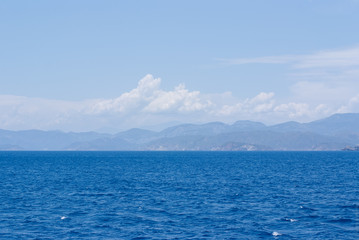 Rocky hills on the horizon under the clouds in the blue sea
