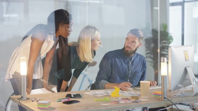 Creative design team brainstorming for ideas in front of computer.