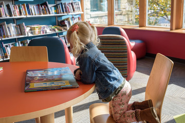 Preschool girl looking at a book at the library
