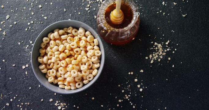 Bowl of cereal rings with honey and honey dipper 