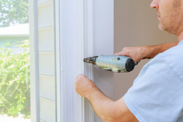 Carpenter using a brad nail gun to complete framing trim Air gun for nailing