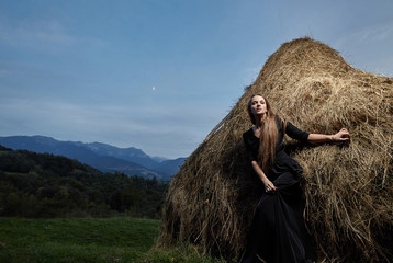 Beautiful girl model in a field near a haystack. Beauty, style, lifestyle, fashion.